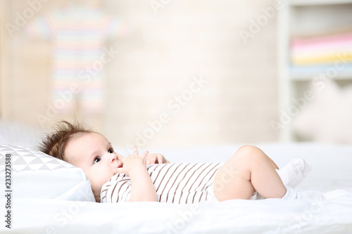Cute baby lying with pillow on white bed