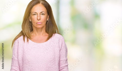 Beautiful middle age adult woman wearing winter sweater over isolated background with serious expression on face. Simple and natural looking at the camera.