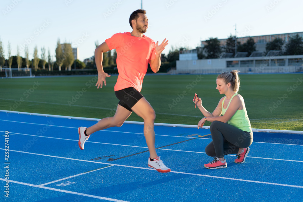 Obraz premium Woman is timing to runner with chronometer at the end of run in a race track. Competition.
