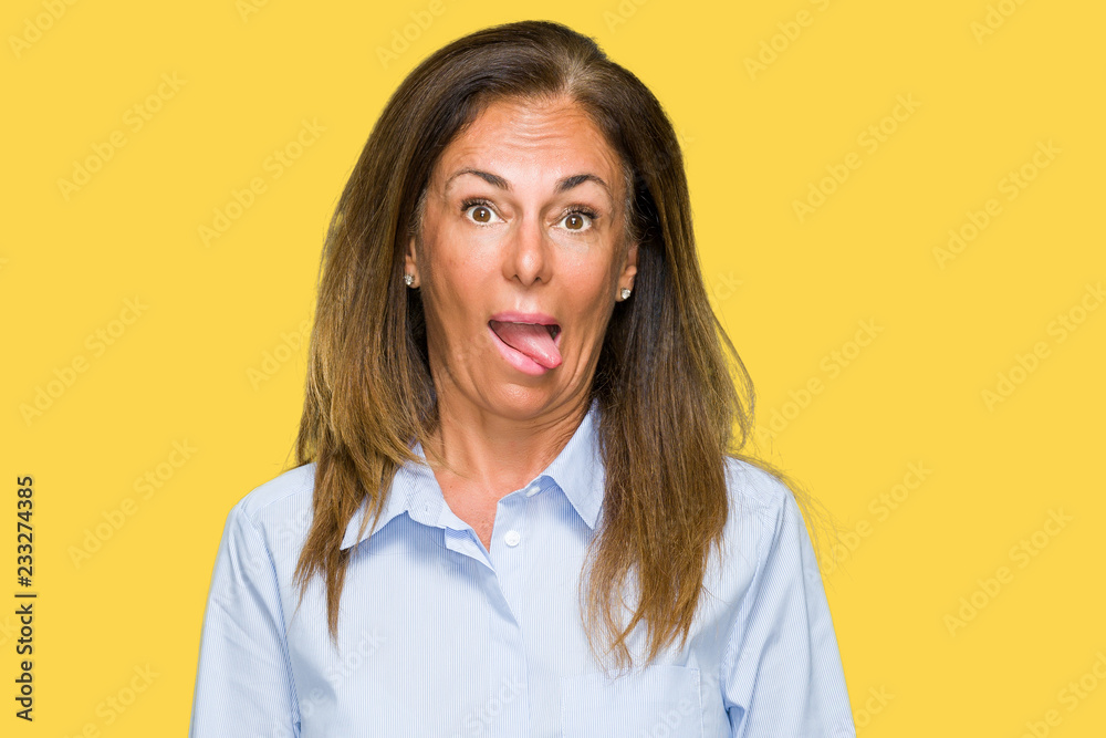 Beautiful middle age business adult woman over isolated background sticking tongue out happy with funny expression. Emotion concept.