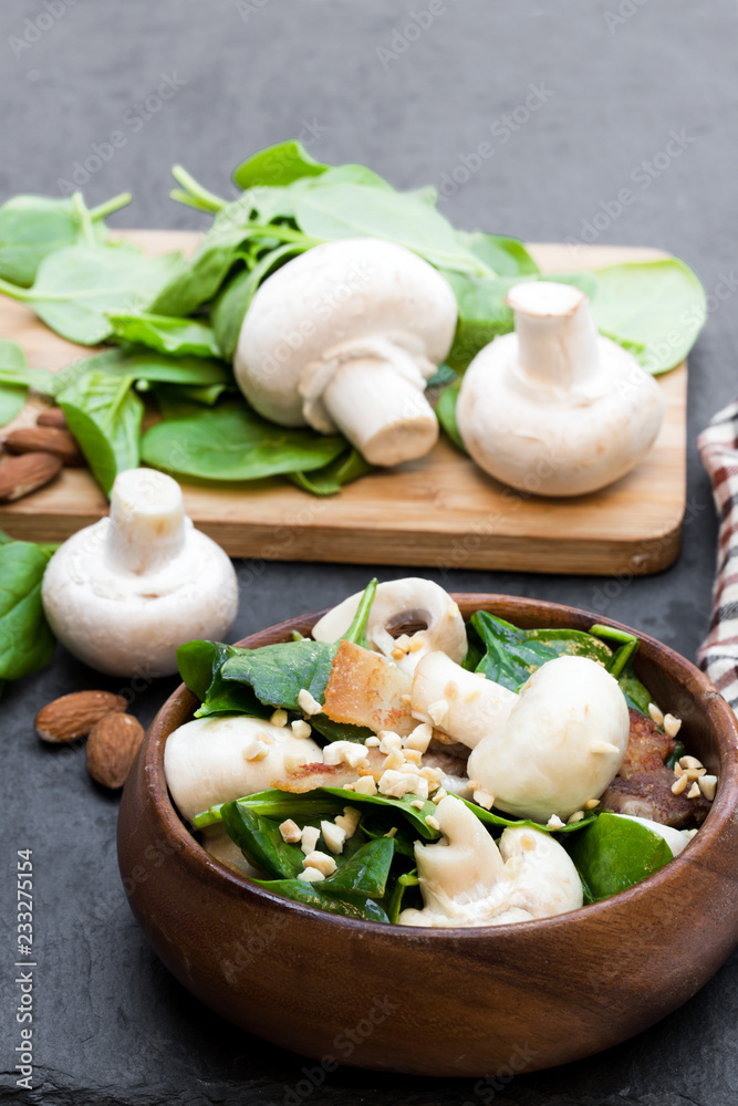 Healthy mushroom salad with spinach and bacon on black stone background Healthy mushroom salad with spinach and bacon on black stone background