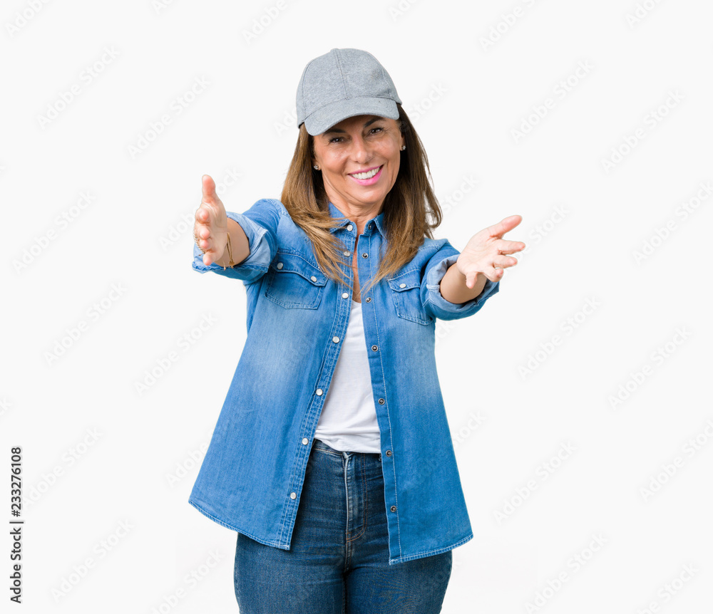 Beautiful middle age woman wearing sport cap over isolated background looking at the camera smiling with open arms for hug. Cheerful expression embracing happiness. Beautiful middle age woman wearing sport cap over isolated background looking at the camera smiling with open arms for hug. Cheerful expression embracing happiness.