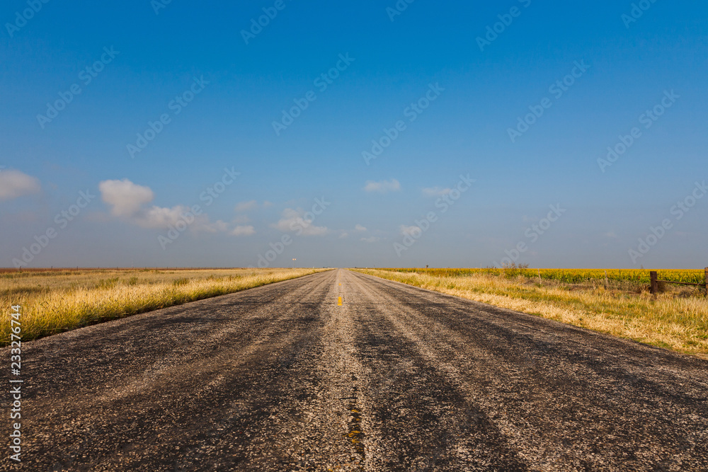 Old black worn country road against blue sky in rural Texas, USA Old black worn country road against blue sky in rural Texas, USA