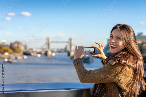 Portrait einer glücklichen Touristin in London beim Fotografieren der Tower Bridge auf ihrer Sightseeing Tour durch die Stadt