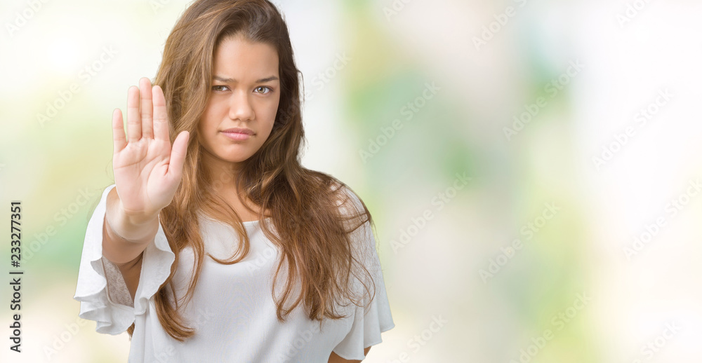 Young beautiful brunette business woman over isolated background doing stop sing with palm of the hand. Warning expression with negative and serious gesture on the face.