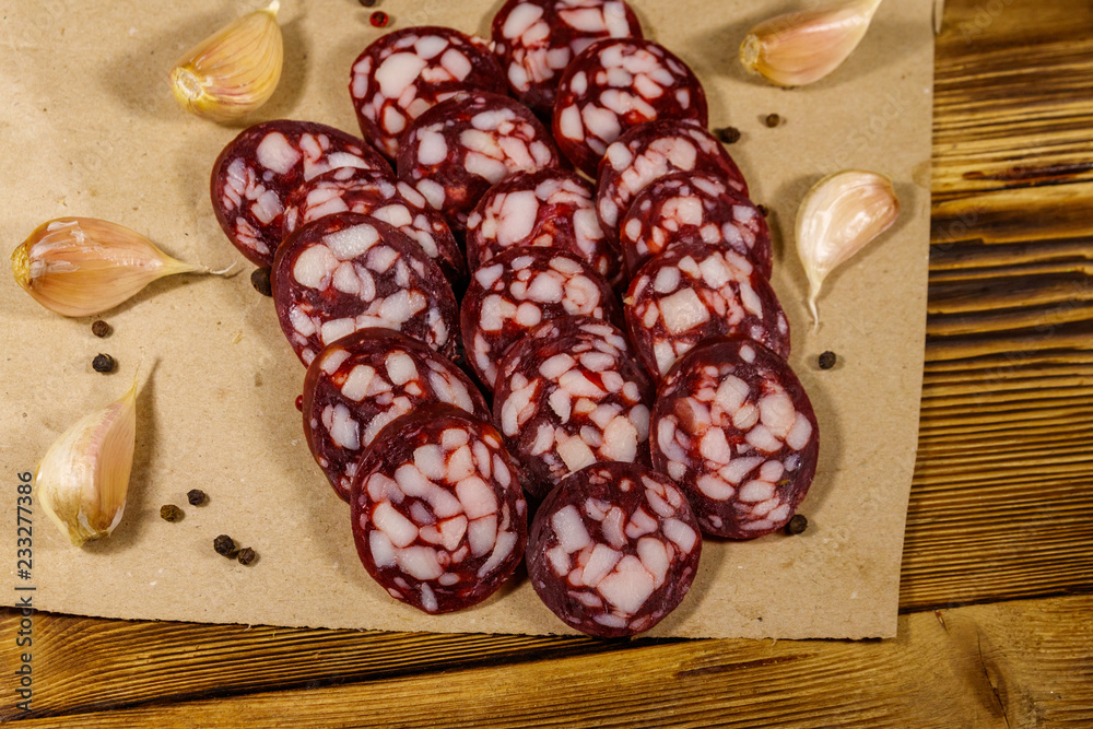 Sliced salami sausage on brown paper on wooden table Sliced salami sausage on brown paper on wooden table