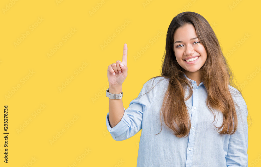 Young beautiful brunette business woman over isolated background showing and pointing up with finger number one while smiling confident and happy. Young beautiful brunette business woman over isolated background showing and pointing up with finger number one while smiling confident and happy.