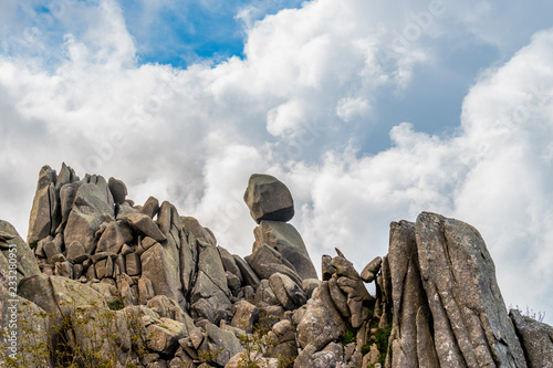 Closeup view of Omu di Cagna (Uomo di Cagna) on the island of Corsica. The granite rock is balanced at the top of a peak on the mountain of Cagna, surrounded by dramatic clouds and blue sky. photo