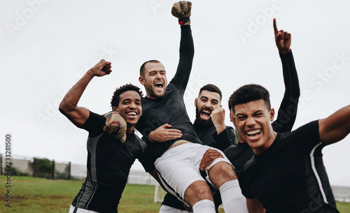 Fototapeta Naklejka Na Ścianę i Meble -  Football players lifting their teammate celebrating victory