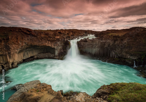 The waterfall Aldeyjarfoss with golden clouds in the sky. The flowing water is captured by a long exposure. Amazing blue color of water from the glacier. Natural and colorful environment. © Petr Šimon