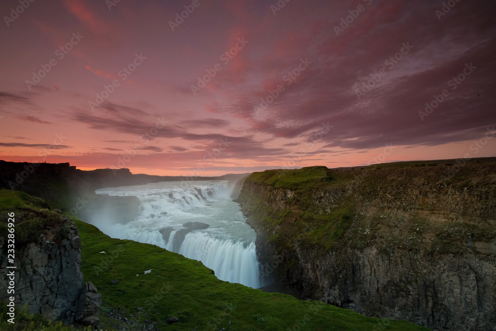The Gullfoss Waterfall with golden clouds in the sky. The flowing water is captured by a long exposure. Amazing blue color of water from the glacier. Natural and colorful environment. The Gullfoss Waterfall with golden clouds in the sky. The flowing water is captured by a long exposure. Amazing blue color of water from the glacier. Natural and colorful environment.