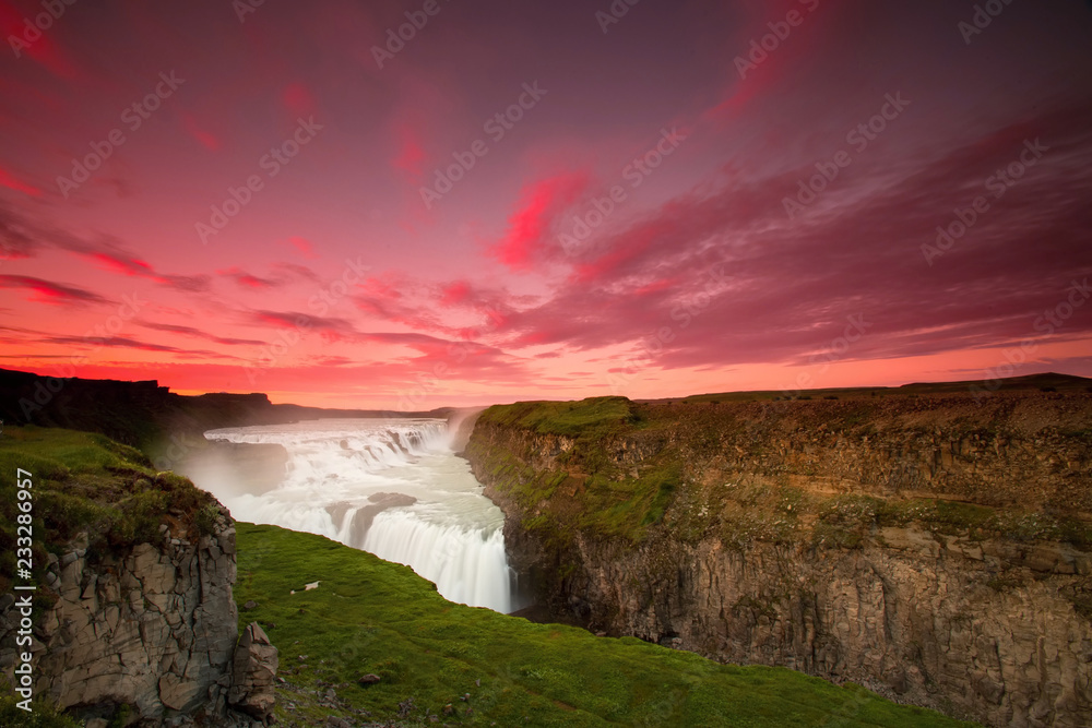 The Gullfoss Waterfall with golden clouds in the sky. The flowing water is captured by a long exposure. Amazing blue color of water from the glacier. Natural and colorful environment. The Gullfoss Waterfall with golden clouds in the sky. The flowing water is captured by a long exposure. Amazing blue color of water from the glacier. Natural and colorful environment.