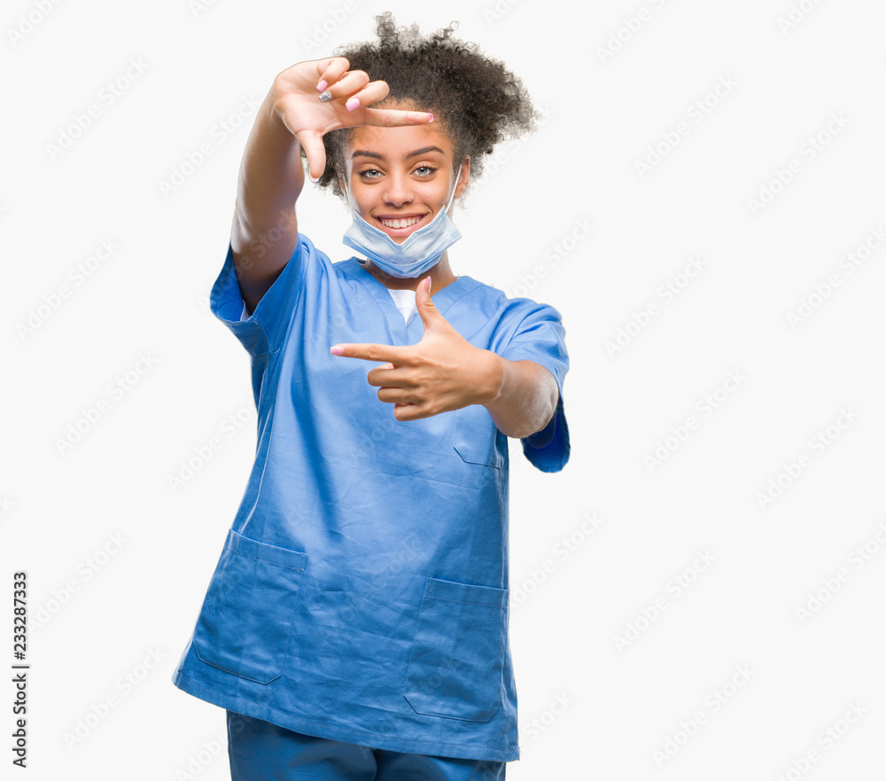 Young afro american doctor woman over isolated background smiling making frame with hands and fingers with happy face. Creativity and photography