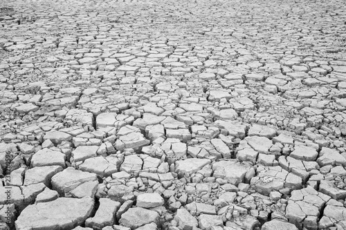 View of cracked and parched soil ground after drought in black and white.