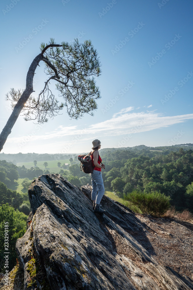 A woman walking on a mountain trail overlooking the valley