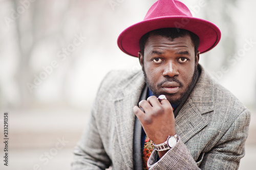 Close up portrait of stylish African American man model in gray coat, jacket tie and red hat. photo
