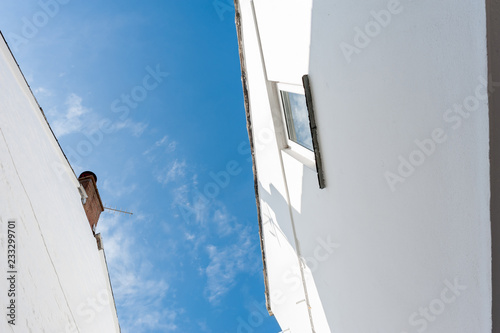 View from below of the sides of two whitewashed buildings in Cornwall, UK.
