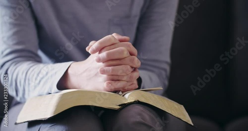 Dolly shot of a woman studying the Bible and praying at home.