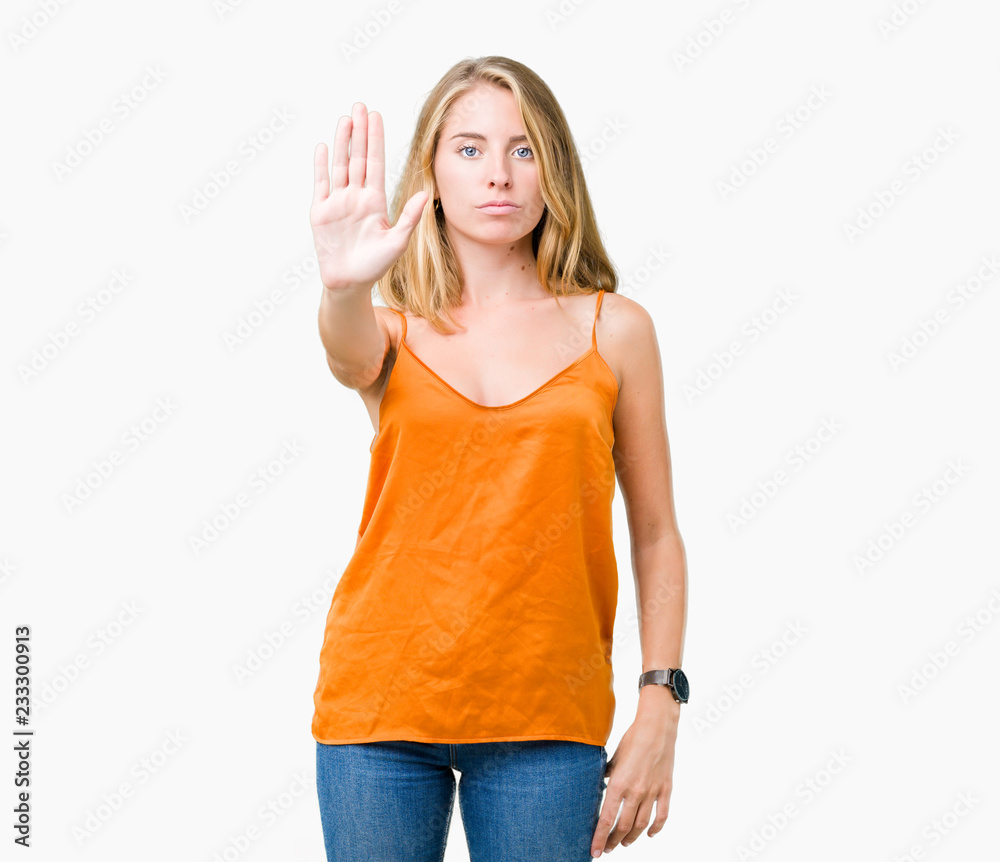 Beautiful young woman wearing orange shirt over isolated background doing stop sing with palm of the hand. Warning expression with negative and serious gesture on the face. Beautiful young woman wearing orange shirt over isolated background doing stop sing with palm of the hand. Warning expression with negative and serious gesture on the face.