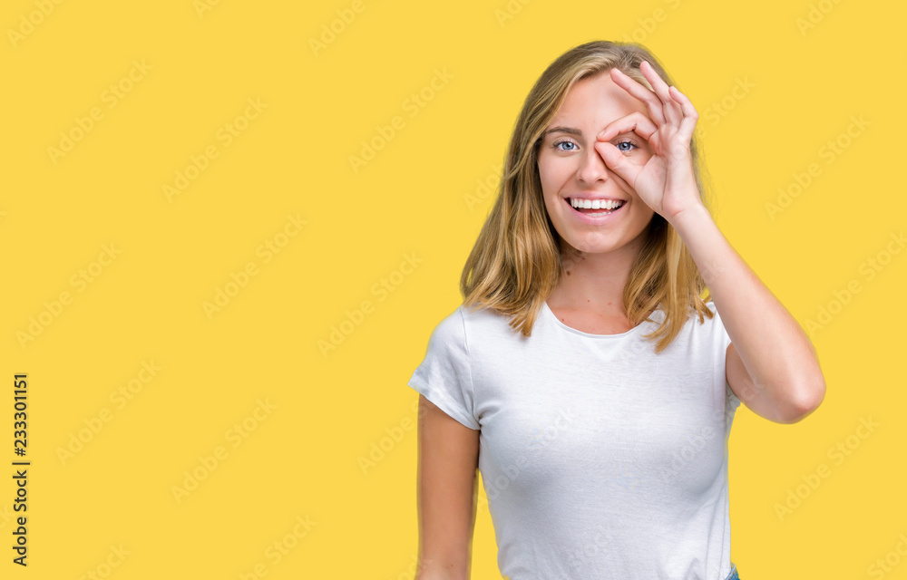 Beautiful young woman wearing casual white t-shirt over isolated background doing ok gesture with hand smiling, eye looking through fingers with happy face. Beautiful young woman wearing casual white t-shirt over isolated background doing ok gesture with hand smiling, eye looking through fingers with happy face.
