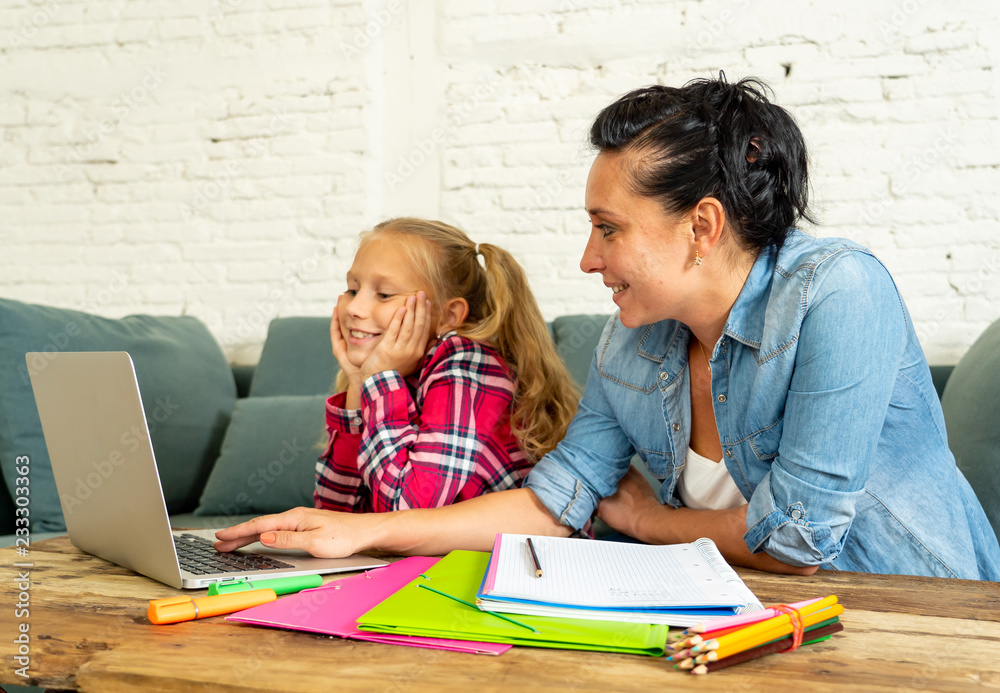 Single mum helping her daughter doing her homework with laptop at home Single mum helping her daughter doing her homework with laptop at home