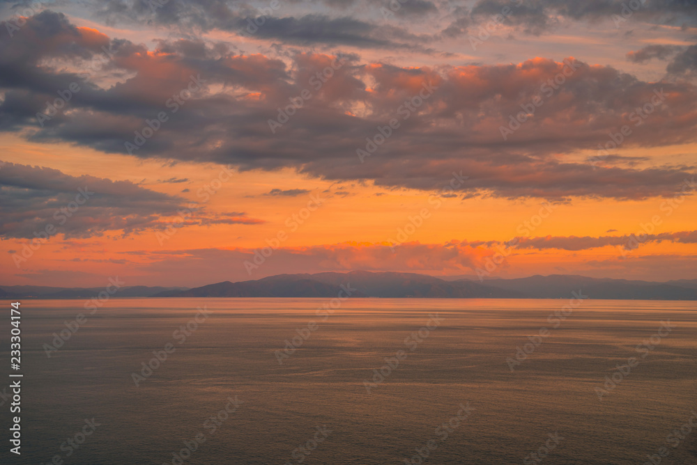 Colorful sunset with dramatic sky background over sea.