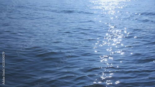 Slow motion shot of sparkling sunlight reflecting off water waves.
