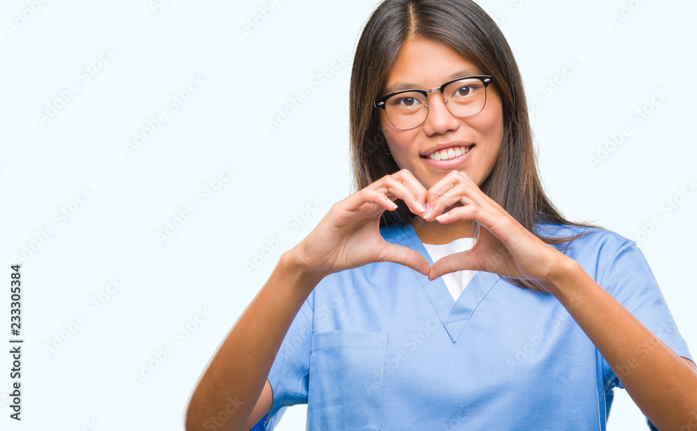 Young asian doctor woman over isolated background smiling in love showing heart symbol and shape with hands. Romantic concept. Young asian doctor woman over isolated background smiling in love showing heart symbol and shape with hands. Romantic concept.