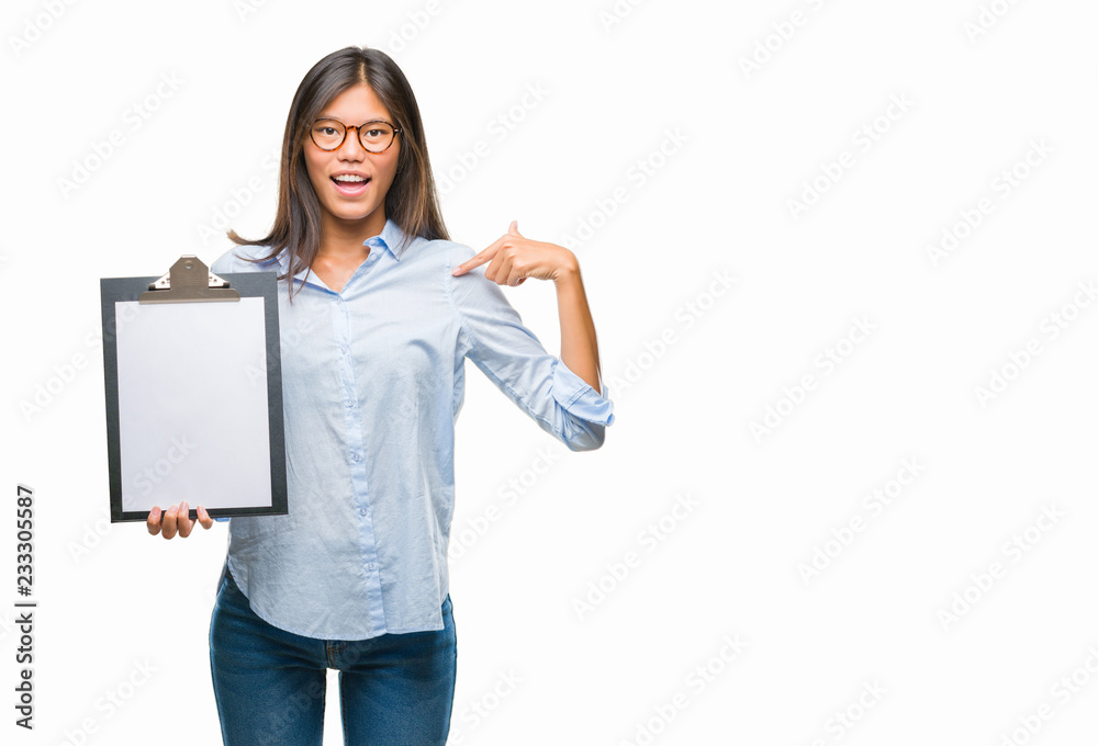 Young asian business woman over isolated background holding clipboard with surprise face pointing finger to himself Young asian business woman over isolated background holding clipboard with surprise face pointing finger to himself