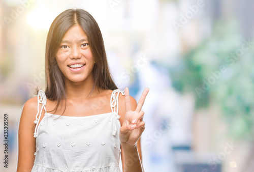 Wallpaper Mural Young asian woman over isolated background smiling with happy face winking at the camera doing victory sign. Number two. Torontodigital.ca