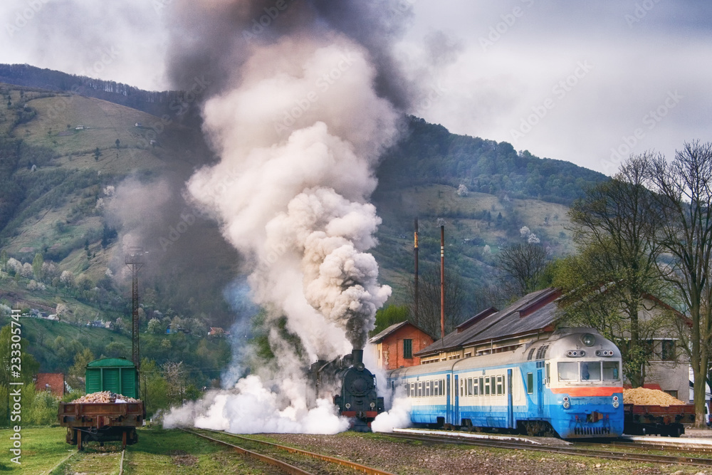 Steam train departure from the station in the mountains. Carpathian landscape, Rahiv, Ukraine. Active vintage transport.