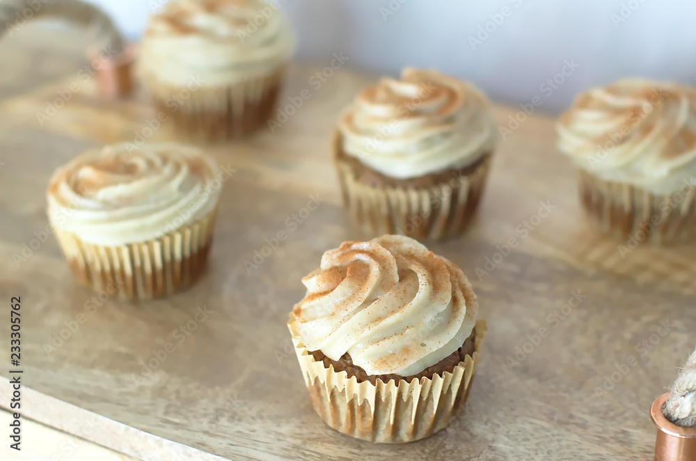 Chai-infused cupcakes with vanilla frosting on a wooden display tray Chai-infused cupcakes with vanilla frosting on a wooden display tray