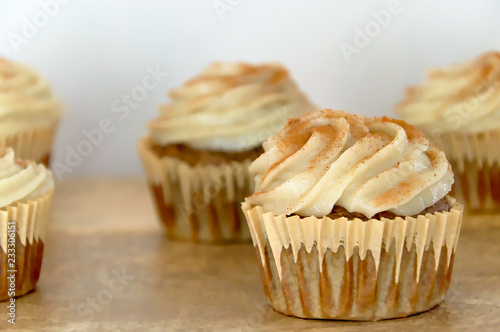 Chai-infused cupcakes with vanilla frosting on a wooden display tray