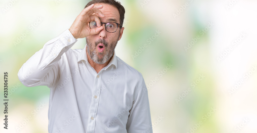 Handsome middle age elegant senior business man wearing glasses over isolated background doing ok gesture shocked with surprised face, eye looking through fingers. Unbelieving expression.