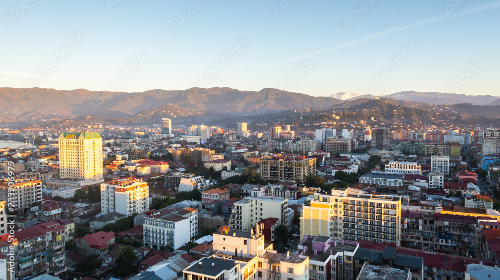 Fototapeta premium Batumi, Adjara, Georgia - October 2018: cityscape seen from the top of Sheraton sky bar during sunset golden hour with mountains in background