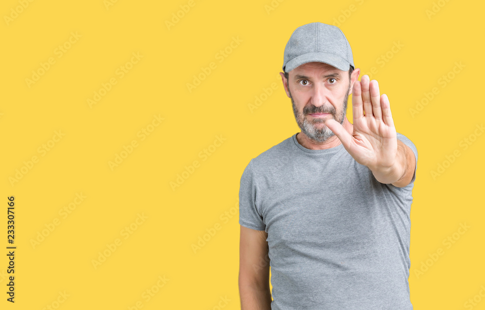 Handsome middle age hoary senior man wearing sport cap over isolated background doing stop sing with palm of the hand. Warning expression with negative and serious gesture on the face. Handsome middle age hoary senior man wearing sport cap over isolated background doing stop sing with palm of the hand. Warning expression with negative and serious gesture on the face.