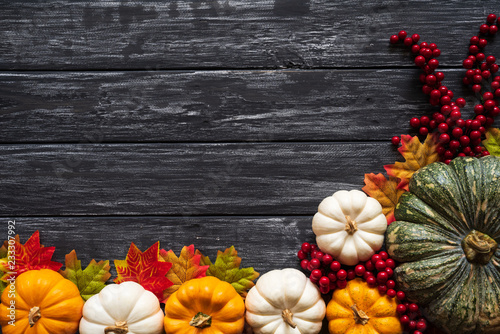 Top view of Autumn maple leaves with Pumpkin and red berries on old wooden background. Thanksgiving day concept.