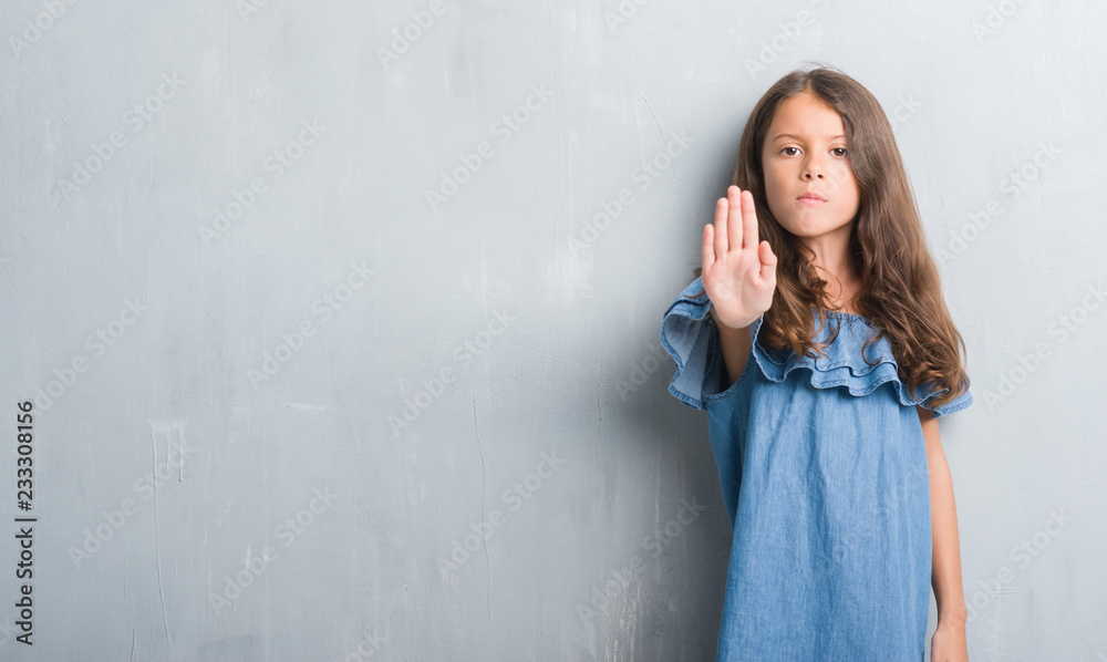 Young hispanic kid over grunge grey wall doing stop sing with palm of the hand. Warning expression with negative and serious gesture on the face. Young hispanic kid over grunge grey wall doing stop sing with palm of the hand. Warning expression with negative and serious gesture on the face.