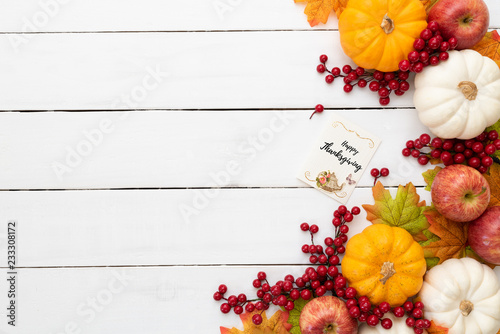 Top view of  Autumn maple leaves with Pumpkin and red berries on white wooden background. Thanksgiving day concept.