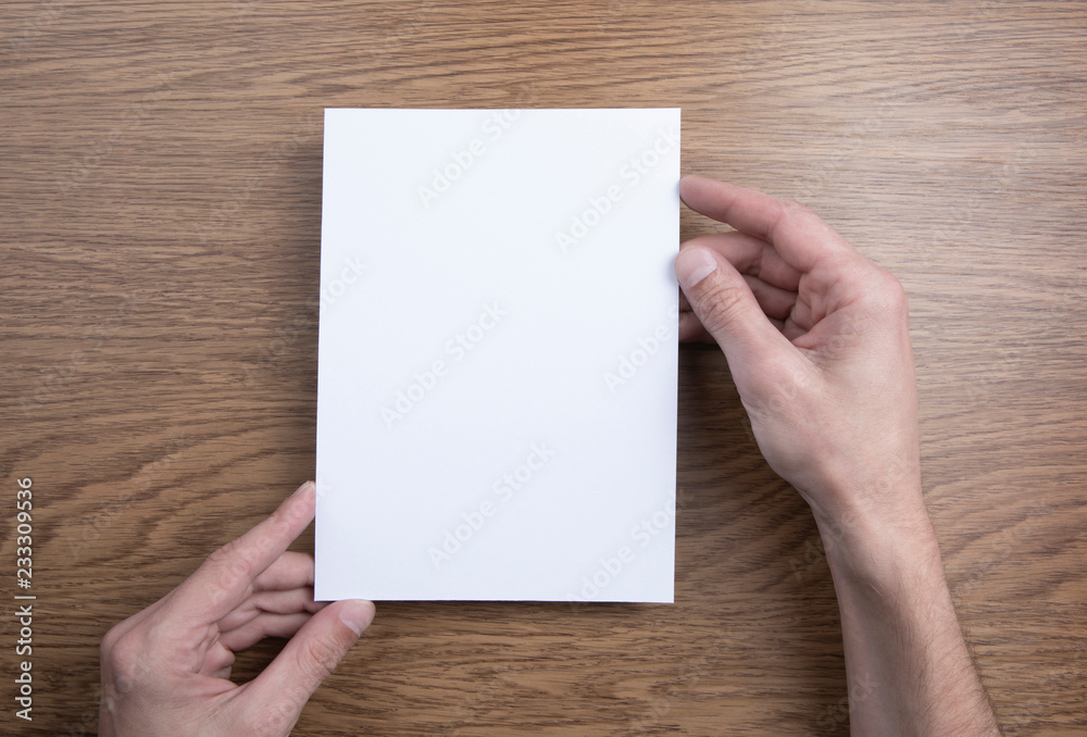 Mens hands holding empty white letterhead Mens hands holding empty white letterhead