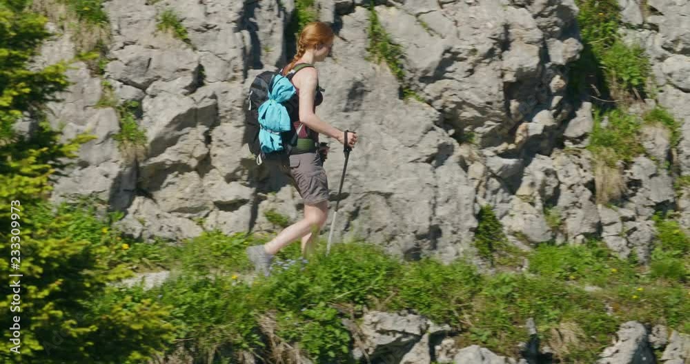 An active woman hiking on the side of a mountain. Tracking shot. An active woman hiking on the side of a mountain. Tracking shot.
