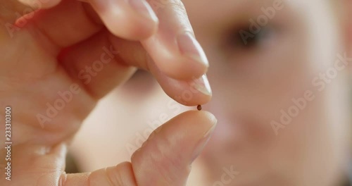 Slow motion closeup of a woman holding a single mustard seed in her hand.