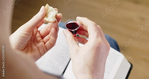 Over the shoulder closeup shot of a woman holding Communion elements over an open Bible.