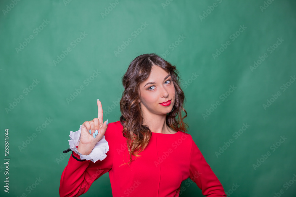 portrait of Attractive happy girl pointing at something. Emotional expressing woman in red dress, red lips and dark curly hairstyle.how product, brand. Gorgeous woman love product. It use for