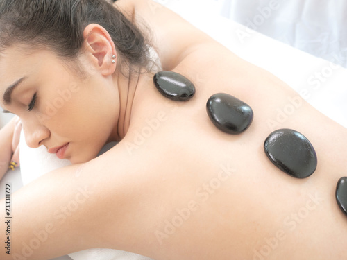 beautiful and healthy woman during a back stone therapy massage in spa salon