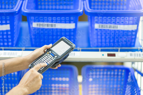 Hands holding portable barcode scanner in warehouse