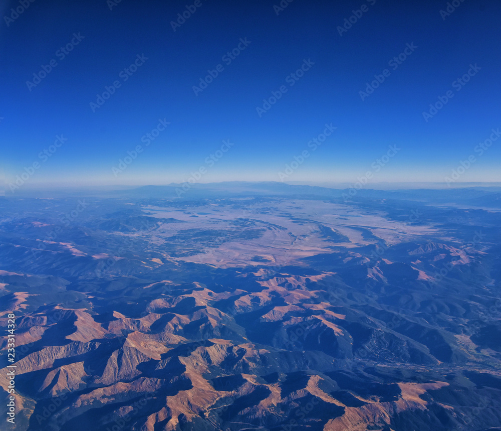 Aerial view of topographical Rocky Mountain landscapes on flight over Colorado and Utah during autumn. Grand sweeping views of rivers, mountain and landscape patterns. Top view, Rockies and Wasatch