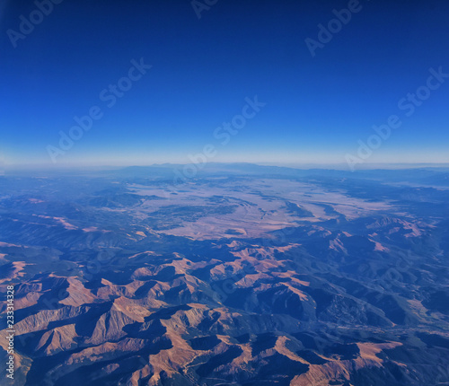Aerial view of topographical Rocky Mountain landscapes on flight over Colorado and Utah during autumn. Grand sweeping views of rivers  mountain and landscape patterns. Top view  Rockies and Wasatch