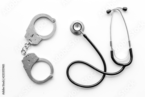 Medical lawsuit. Arrest for medical crime concept. Handcuff near stethoscope on white background top view