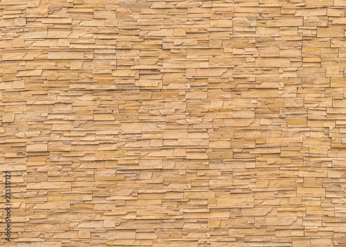 Rock stone brick tile wall aged texture detailed pattern background in yellow brown color